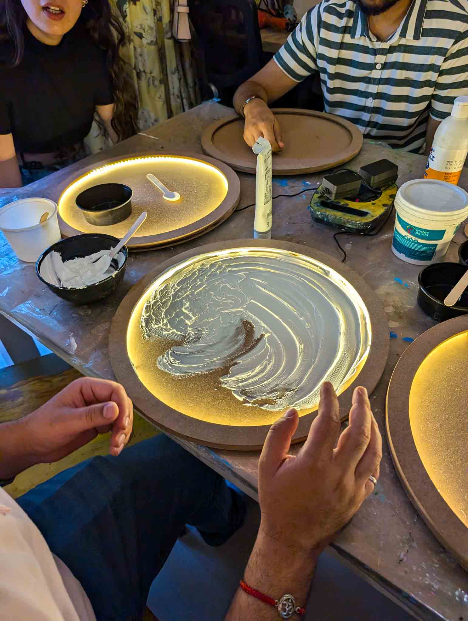 Participants spreading white paste on round moon lamp base under warm light